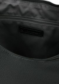 Zwarte textuur leer interieur van een tas, met een ritscompartiment en een gladde, matte voering zonder zichtbare patronen of accenten.