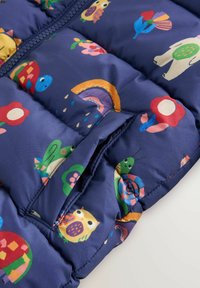 Giacca imbottita in tessuto blu navy con animali cartoon colorati, fiori e motivi; presenta una zip e sezioni trapuntate per l'isolamento.