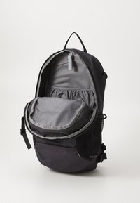 Zaino nero con un flap grigio, chiusura con cerniera, tasca laterale in rete e una tasca interna; realizzato in tessuto resistente con una superficie liscia.