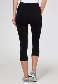 Černé capri legíny s vysokým pasem, vyrobené z elastického materiálu. Mají hladkou strukturu a minimalistický design.