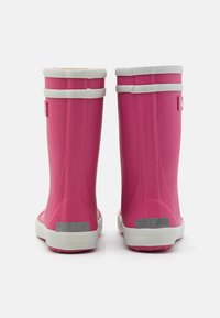 Bottes de pluie en caoutchouc rose avec des accents blancs, présentant une texture lisse, une hauteur jusqu'au mollet, et des patches réfléchissants argentés à l'arrière.