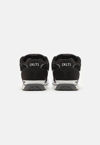 Adidași negri cu un superior din suede și plasă, având o bandă de accent albă și branding [XLT] pe călcâi. Talpă din cauciuc texturat.