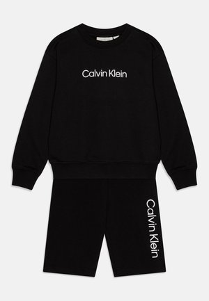 Ensemble de vêtements d'intérieur en coton noir comprenant un sweat-shirt à manches longues et un short. Le sweat-shirt arboré le logo blanc "Calvin Klein". Design simple, coupe décontractée.