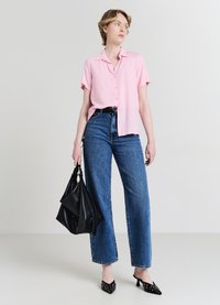 Chemise rose à manches courtes boutonnée, jean large en denim bleu taille haute, sac à main noir et mules à talons noires pointues avec des accents œillets.