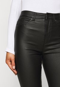 Black faux leather pants with a high waist, front zipper, and button closure. Features subtle sheen and classic five-pocket design.