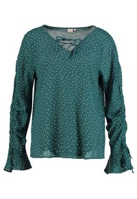 Türkisfarbene Bluse mit langen Ärmeln und weißen Sprenkel-Muster, V-Ausschnitt mit Schnürdetails, geraffte Ärmel mit Bändern, weicher Stofftextur.