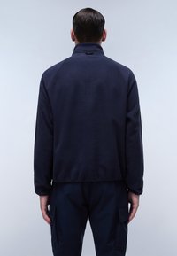 Marineblaue Fleecejacke mit hohem Kragen, Raglanärmeln und einem leicht verkürzten Design. Weiche Textur, keine sichtbaren Metallteile oder Muster.