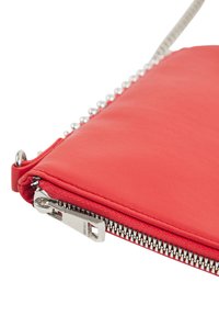 Clutch in pelle rossa con accessori in metallo argentato, dotata di chiusura con zip e accenti decorativi lungo il bordo. Texture liscia.