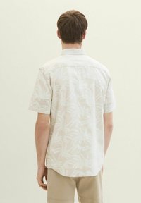 Kurzärmliges, hellbeiges Hemd mit einem Palmenblattmuster, aus einem leichten Stoff gefertigt, mit einem klassischen Kragen und einem geraden Schnitt.