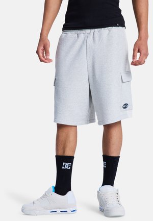 Szare bawełniane szorty cargo z sznurkiem w pasie, bocznymi kieszeniami i naszywką z logo, zestawione z czarnymi skarpetkami i białymi trampkami.