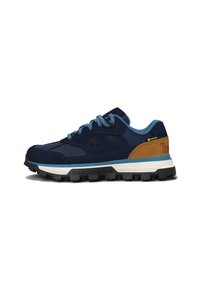 Zapatilla azul marino con material de ante y malla, que presenta un acento de cuero marrón claro, suela texturizada y cordones turquesa. Logo de "Timberland" visible.