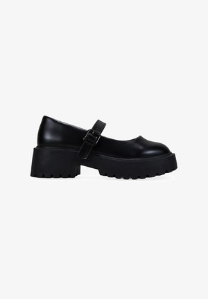 Zapatos Mary Jane de plataforma negra con punta redonda, suela de goma y correa ajustable en el tobillo. Material suave y brillante con una suela texturizada.