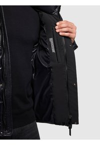 Črno zunanjo jakno z gladko, sijočo teksturo, ki ima zadrgo, pritrdilne gumbe in notranji žep.