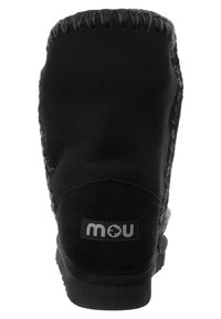 Stivale alla caviglia in suede nero con cuciture testurizzate, tacco rinforzato e patch con marchio. Fodera morbida indicata sul bordo superiore e sulla suola.