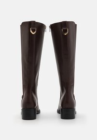 Bottes marron en cuir jusqu'au genou avec une texture lisse, fermetures éclair latérales, accents de métal doré, et un talon bas noir uni.