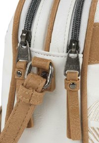 Bolso de cuero sintético blanco con acentos de cuero marrón, que cuenta con dos cremalleras plateadas, correas ajustables y costuras decorativas.