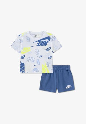 Bijela košulja kratkih rukava s plavim i žutim Nike logotipima u kombinaciji s plavim Nike šortama s elastičnim pojasom.