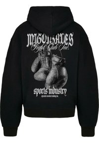 Fekete kapucnis felső, amelyen egy grafikai nyomtatás található bokszkesztyűkről a hátsó részen, fehér szöveggel, amely tartalmazza a "MIGOLARES Fight Club Inc." és a "sportipar" feliratokat.