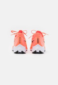 Baskets de course rose fluo avec une tige texturée, des accents noirs et des semelles blanches. Présente une forme arrondie et des lacets contrastants.