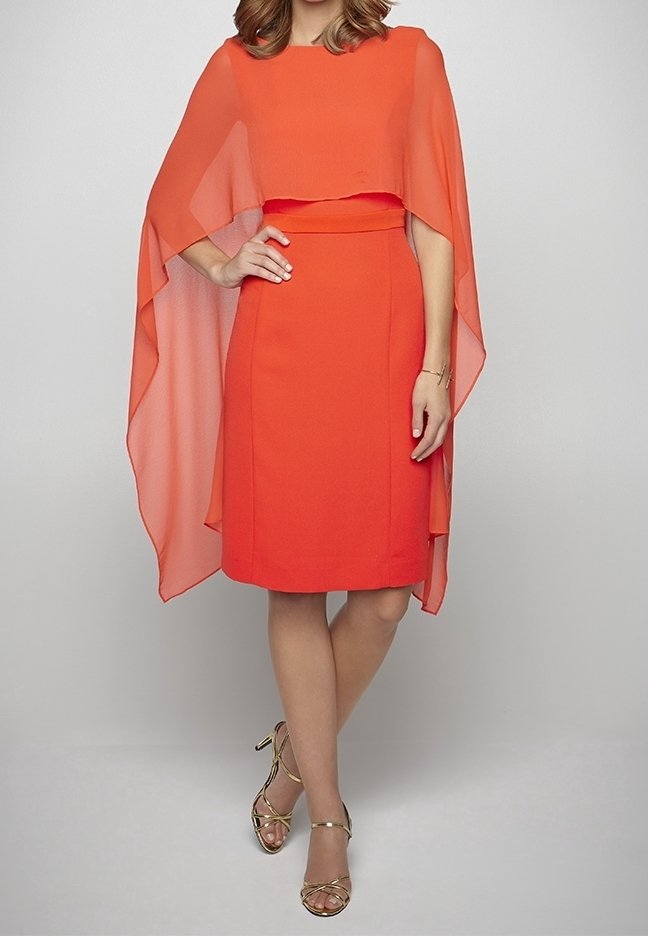 Robe orange avec un corsage ajusté et des manches en cape fluides. La robe est à la hauteur du genou avec une silhouette structurée. Sandales dorées à lanières.
