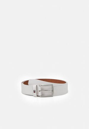 Ceinture en cuir blanc roulée avec une boucle rectangulaire argentée et un petit logo Tommy Hilfiger sur la boucle de la ceinture.