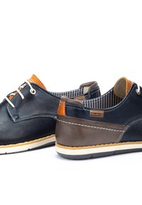 Scarpe casual da uomo in pelle blu scuro e marrone, con accenti arancioni e cuciture bianche, dotate di una soletta testurizzata e lacci rotondi.