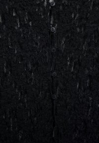 Schwarzer Cardigan mit Textur, der ein lockeres Strickmuster, sechs schwarze Knöpfe und ein entspanntes Design aufweist.