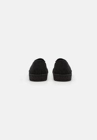 Sorte slip-on sko med en teksturert overflate, rund tå og flette-såler. Har mykt yttermateriale og minimalistisk design.