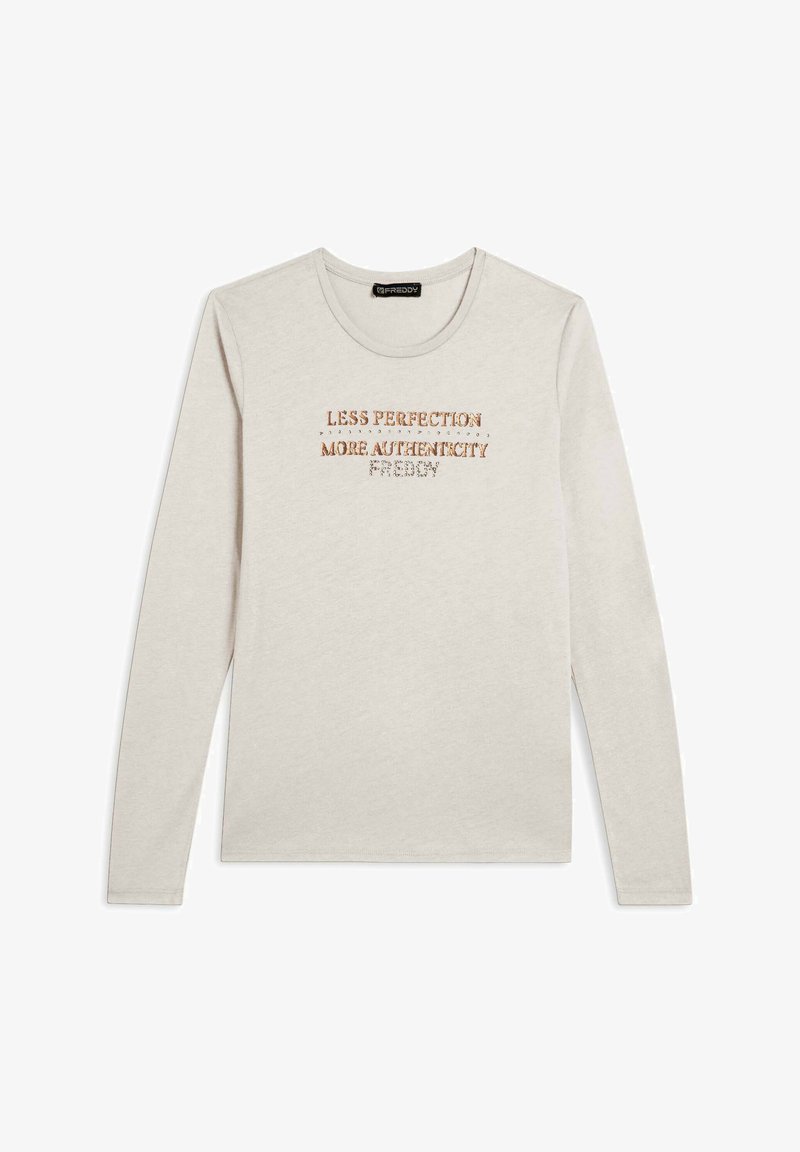 Chemise à manches longues en coton beige clair avec un col rond. Arbore un texte imprimé en doré métallique et en marron : "MOINS DE PERFECTION, PLUS D'AUTHENTICITÉ."