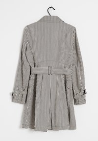 Manteau rayé noir et blanc avec un col, taille ceinturée et manches retroussées. Présente des rayures verticales et un design fluide.