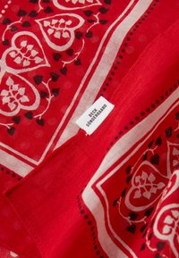 Écharpe rouge avec des motifs de cœurs et de fleurs en noir et crème. Fabriquée en tissu léger, avec une étiquette portant la mention "Beck Söndergaard."