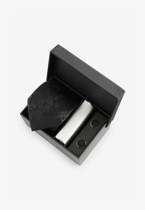 Papion negru cu un model floral, batistă albă pentru buzunar și butoni de manșetă argintii într-o cutie neagră. Material texturat cu modele intricate.