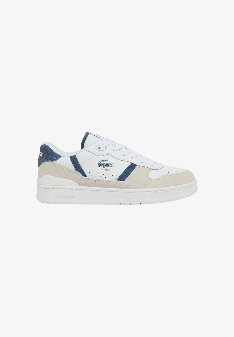 Zapatilla blanca con parte superior de cuero liso, acentos en ante azul, detalles perforados y suela de goma blanca texturizada. Logo de Lacoste visible.