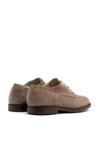 Zapatos de hombre de ante marrón con una textura suave, punta redondeada y detalles de costura mínimos. Las suelas de goma ofrecen tracción y estabilidad.