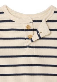 Ribbed cream-colored shirt with navy horizontal stripes, featuring a buttoned neck placket and three wooden buttons.