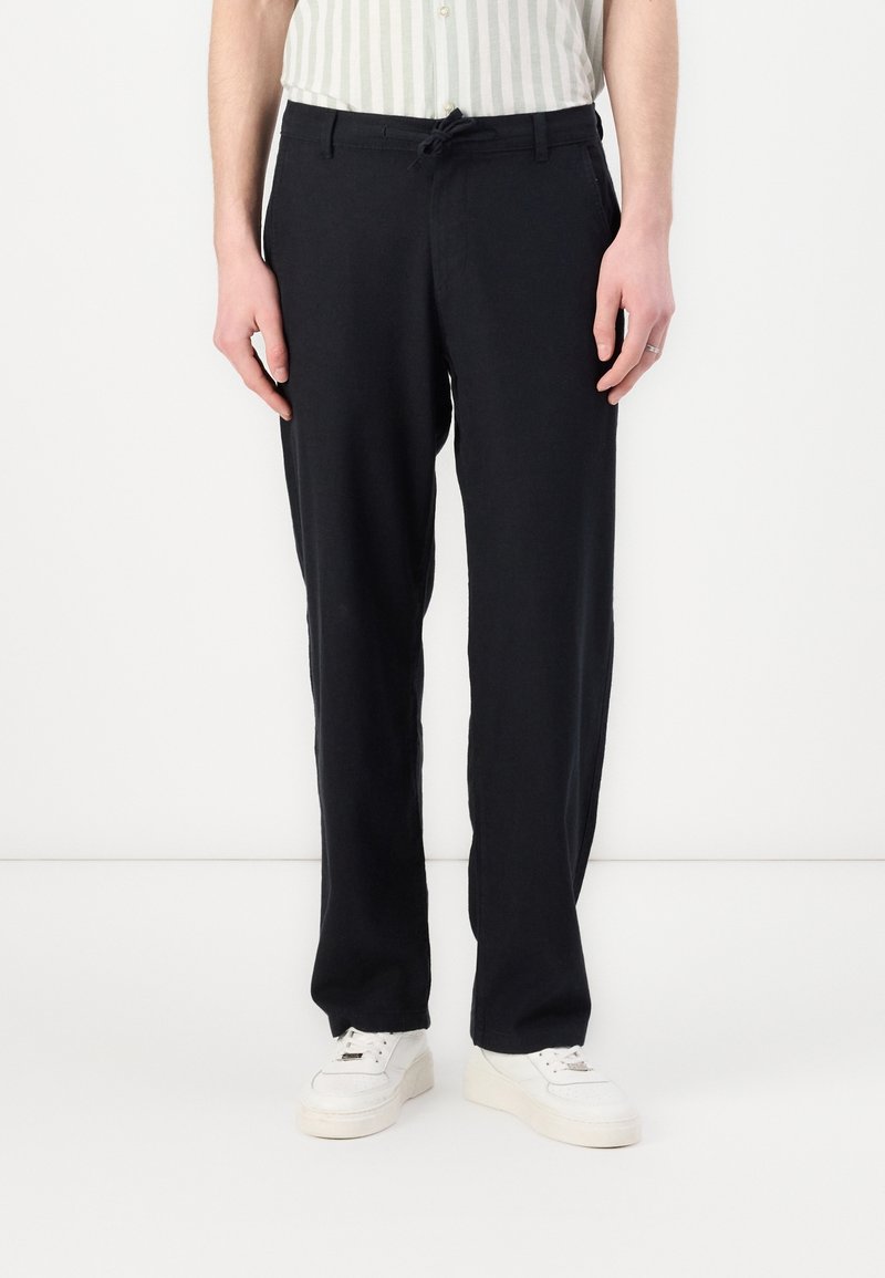 Black, relaxed-fit pants with a drawstring waist. Made of lightweight fabric, featuring subtle side pockets with a smooth texture.