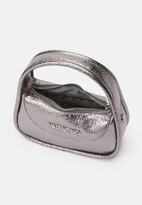 Stříbrná metalická kabelka s texturovaným povrchem, zaobleného tvaru, na zip a s krátkým držákem. Na přední straně se nachází logo "Valentino".