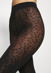 Crne prozirne tajice s uzorkom leopard printa, teksturiranim materijalom i glatkim crnim pojasom. Prilagodljiv dizajn naglašava oblik nogu.