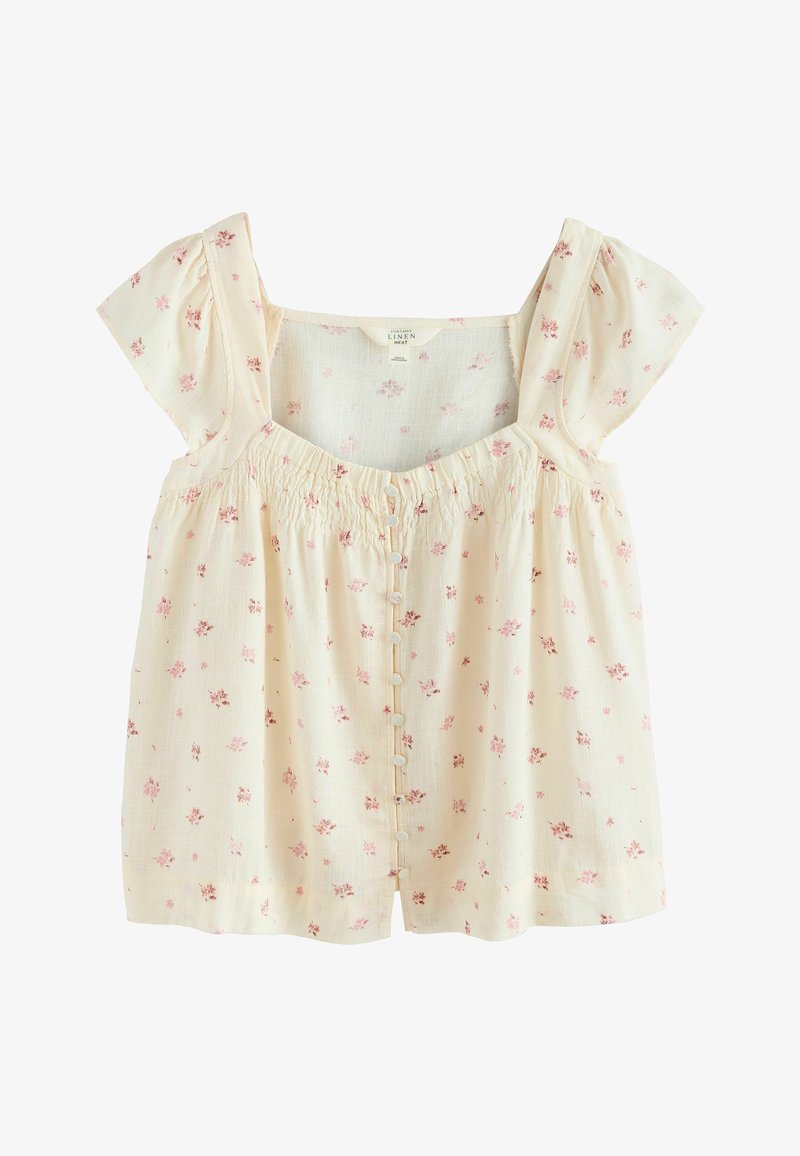 Blouse couleur crème avec un motif floral rose, manches courtes volantées, encolure carrée froncée et fermeture à boutons sur le devant.