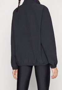 Czarna, oversize kurtka z wysokim kołnierzem, elastycznym dołem i mankietami, o gładkiej fakturze i luźnym kroju.