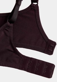 Brasiletta di un viola scuro con spalline regolabili, tessuto morbido e chiusura a gancio. Presenta una consistenza morbida e un design senza cuciture.