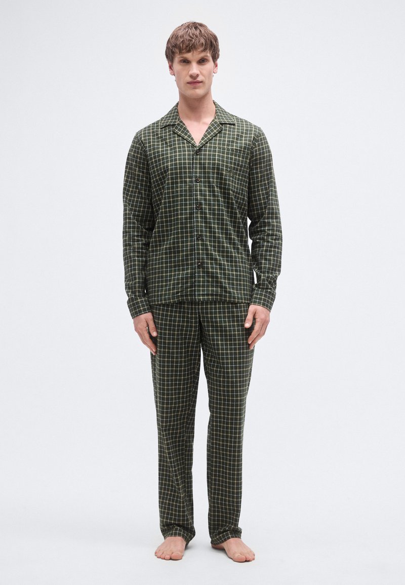 Conjunto de pijama de cuadros verdes hecho de tela suave. Cuenta con una camisa abotonada con bolsillo y pantalones a juego con cintura elástica.