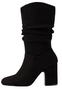 Mustat nilkkurit, jotka on valmistettu pehmeästä sametista, löysällä muotoilulla, pyöreillä kärjillä ja puolella olevalla korkolla. Ominaisuuksiin kuuluu sileä pinta ja minimaalinen ompelutyyli.