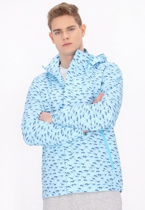Lichtblauwe jas met een all-over donkerblauw dierenpatroon. Beschikt over een rits aan de voorkant, capuchon en elastische manchetten voor aanpassing.