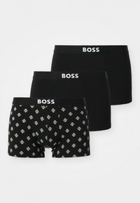 Trois paires de boxers : deux noirs unis avec une ceinture à logo et un à motifs noirs avec des formes de diamant en blanc et accents dorés.