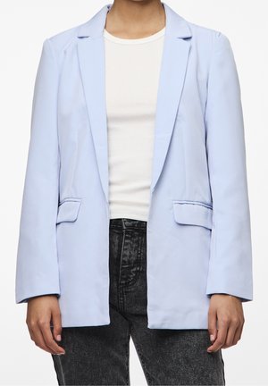 Blazer azzurro chiaro realizzato in tessuto morbido, con maniche lunghe, due tasche frontali e una vestibilità comoda. Indossato sopra una maglietta bianca.