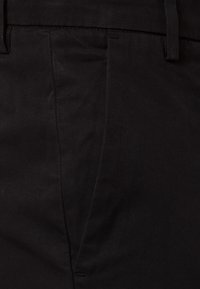 Černé kalhoty z tkané látky, s přímým střihem, hladkou texturou a pečlivě prošitými švy.