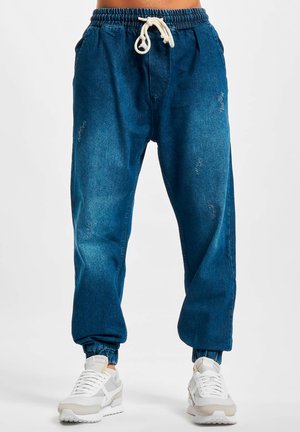 Kék denim jogger nadrág, elasztikus derékpánttal, állítható zsinórral és cuffed bokával. Megjelenését díszített részletek és oldalsó zsebek dobják fel.