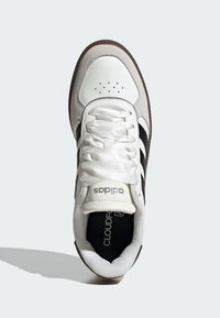 White sneaker with a leather and suede upper, black stripes, round toe, padded collar, and textured laces. Features "CLOUDFOAM" on the insole.