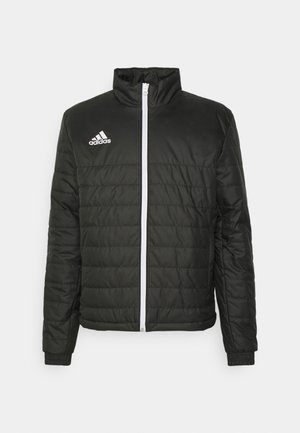 Svart vadderad jacka med hög krage, vit dragkedja och vit Adidas-logotyp på bröstet. Har ett quiltat mönster och ribbade ärmslut.